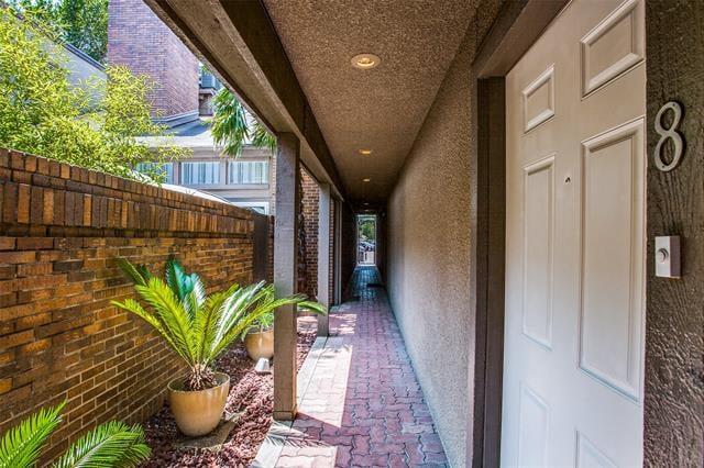 Unit 8 entry with a white paneled door, brick walkway, and potted palm.