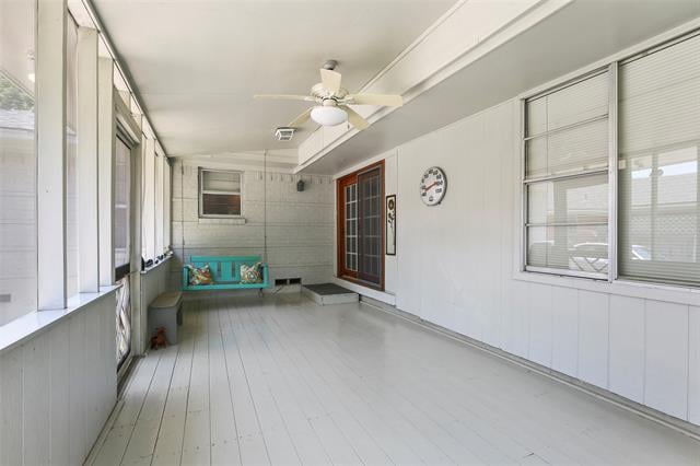 Enclosed sunroom with a turquoise bench swing and windows along both sides.