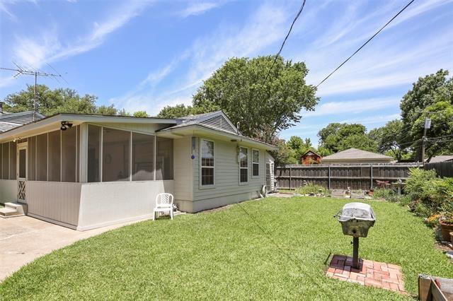 Single-story home with a screened porch overlooking a fenced lawn and brick patio with a grill.