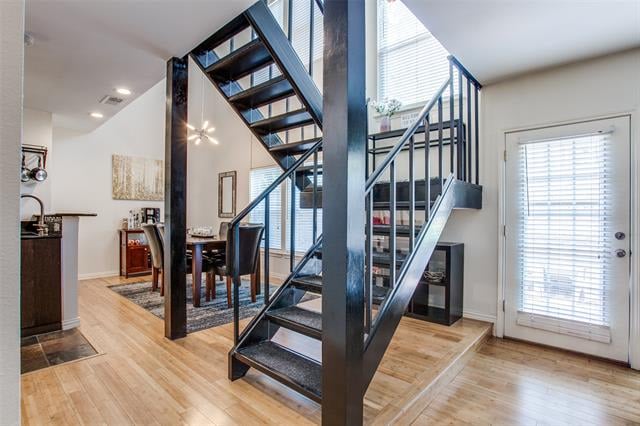 Condo entry and dining area with light wood floors and a prominent black open-riser staircase.
