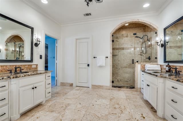 Spacious bathroom with matching white vanities and an arched stone shower.