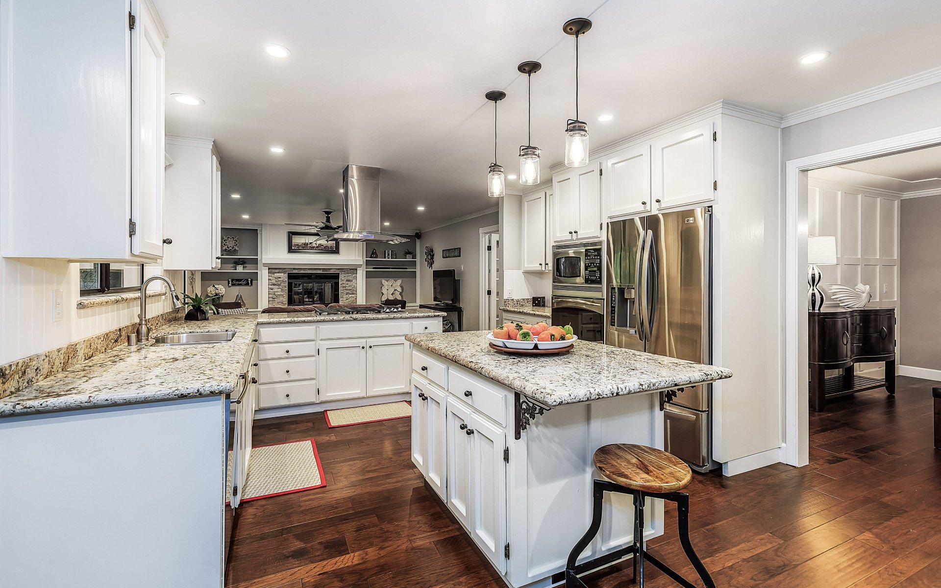 Kitchen with a granite-topped island, white cabinetry, and stainless steel appliances.