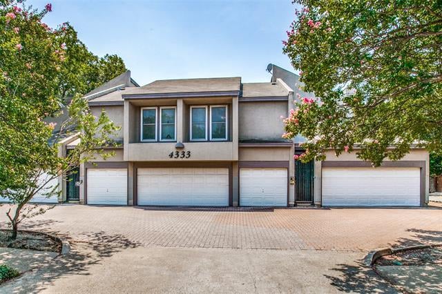 Attached two-story residence with multiple garage doors and flowering trees framing the paved driveway.