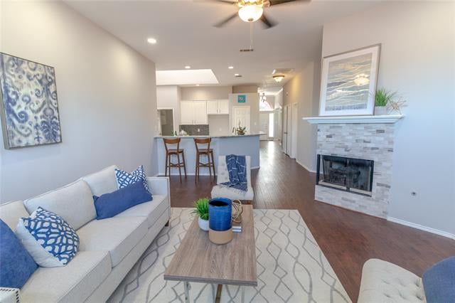 Staged living room with blue-and-white seating, a tiled fireplace, and an open kitchen beyond.