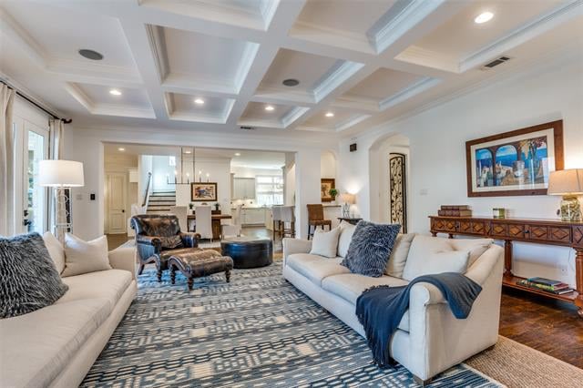 Living room with pale sofas, a patterned rug, and a white coffered ceiling.