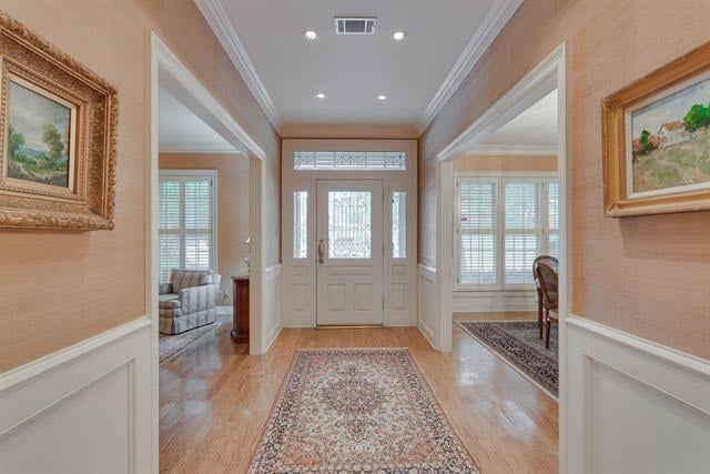 Entry hall with a glass-paneled front door, hardwood floors, and patterned rugs.