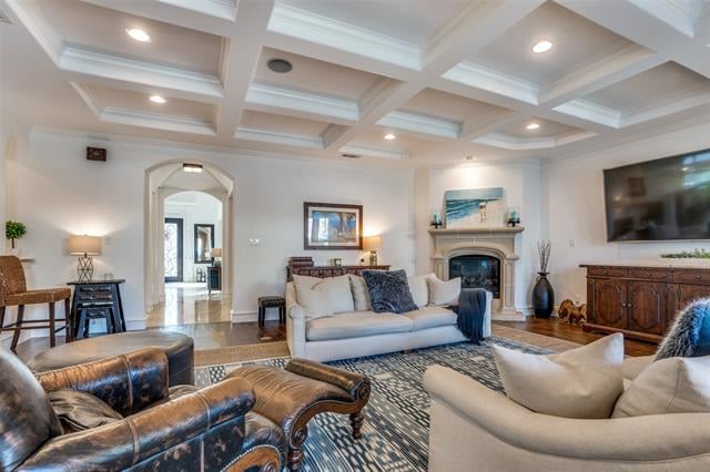 Living room with a coffered ceiling, cream sofas, leather armchairs, and a fireplace.