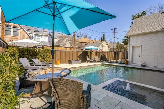 Backyard swimming pool and spa beside a furnished patio shaded by a turquoise umbrella.