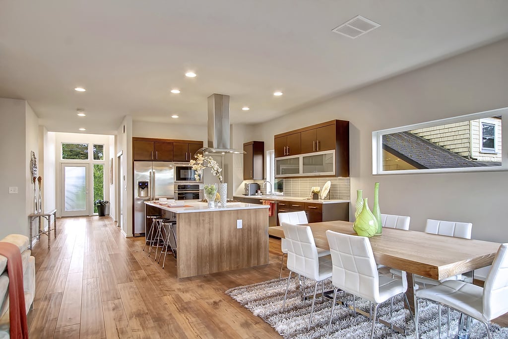Open-plan kitchen and dining area with a wood island, stainless steel appliances, and a long dining table.