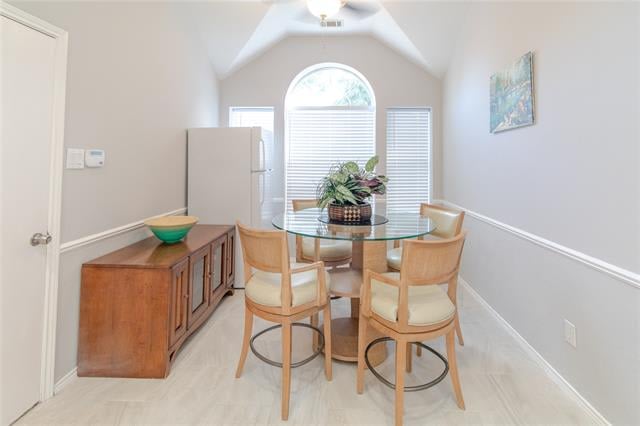Dining area with a glass-top table, four wooden chairs, and a tall arched window.