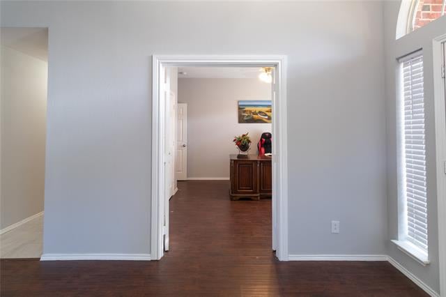 Interior doorway with dark wood floors, light gray walls, and a shuttered window.