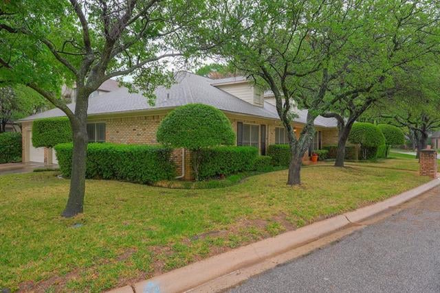 Brick home with trimmed hedges and mature trees along the front yard.