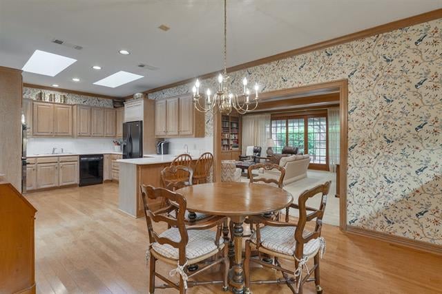Kitchen and dining area with light wood cabinets, a round table, floral wallpaper, and a chandelier.