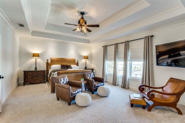 Primary bedroom with a tray ceiling, large curtained windows, and a leather seating area.