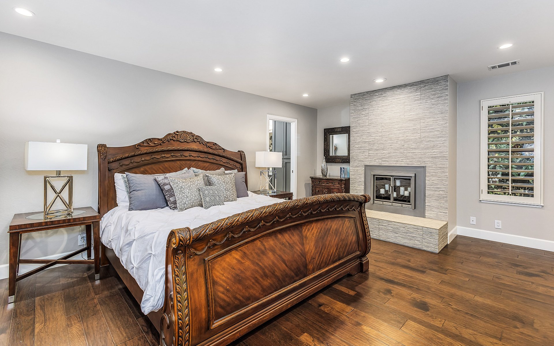 Furnished bedroom with an ornate carved wooden bed and a modern tiled fireplace.