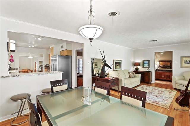 Open-plan dining and living room with a glass table, cream sofas, and hardwood floors.