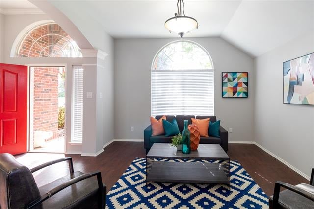 Staged living room with teal sofa, geometric rug, arched window, and open red front door.