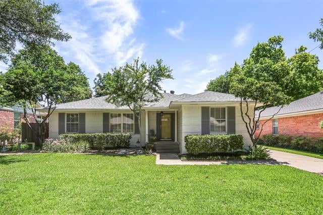 Single-story house with dark shutters, mature trees, and a broad green front lawn.