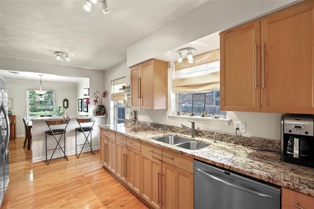 Kitchen with wood cabinetry, granite counters, a double sink, and a breakfast bar.