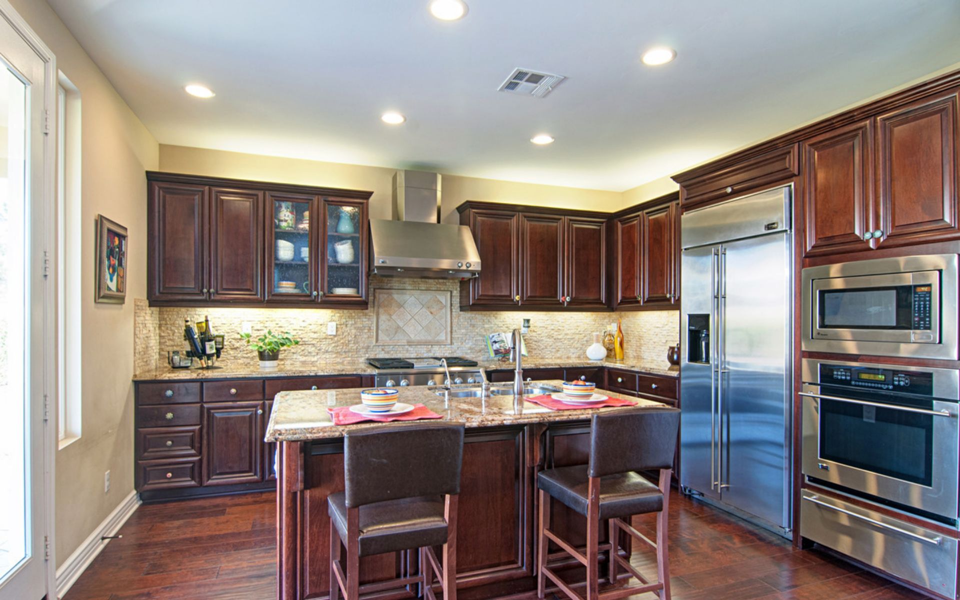 Kitchen with a stone-topped island, dark wood cabinets, and stainless steel appliances.