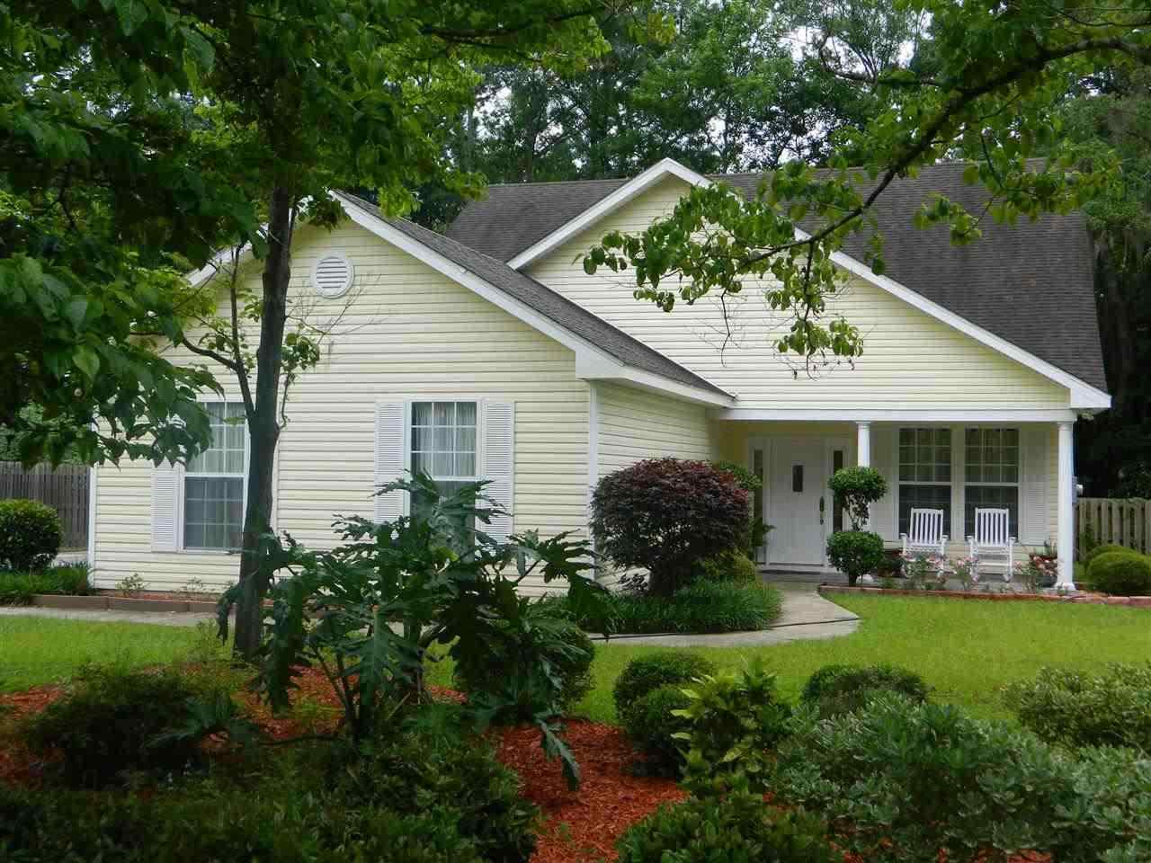 A charming home with a well-kept yard and trees adorning the front, creating a welcoming atmosphere.