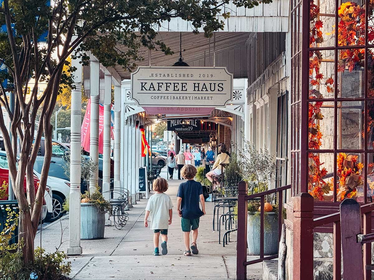 Downtown shopping street with the Kaffee Haus storefront and autumn leaves in the windows.