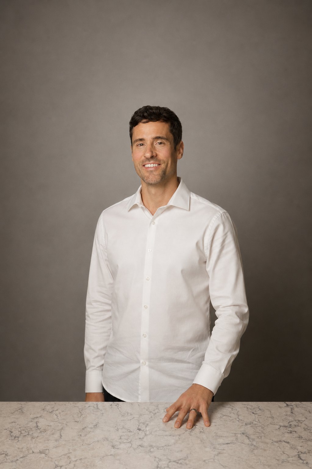 Marcus Taylor in a white shirt, standing behind a marble counter.