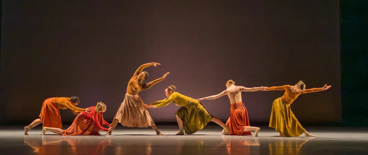 Six dancers in earthy-toned costumes performing on a stage during the LINES Seniors' Performance at the Yerba Buena Center for the Arts.