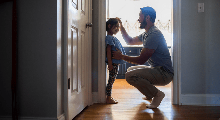 A person kneeling down to talk to a child by a doorway, possibly discussing moving or other significant decisions.