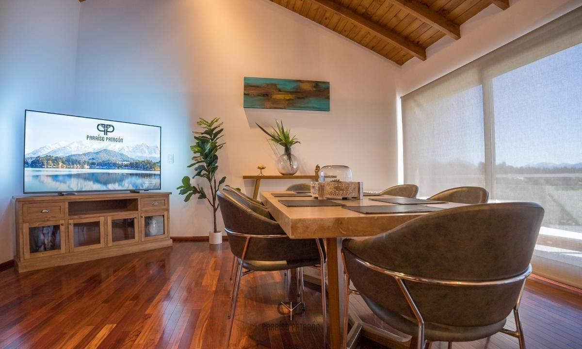 Furnished dining area with a wooden table, upholstered chairs, and vaulted wood ceiling.