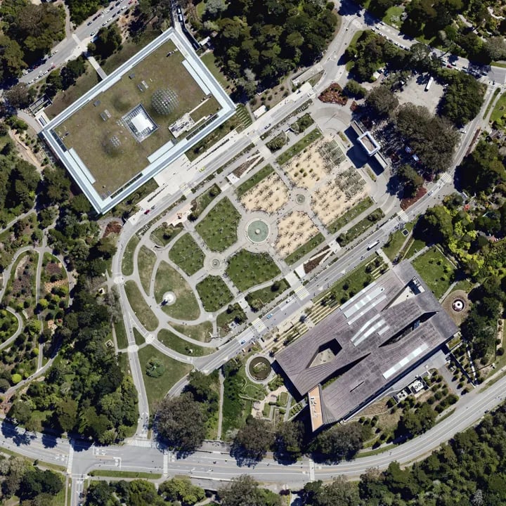 Aerial view of the Music Concourse showing the de Young Museum, California Academy of Sciences, and surrounding park landscape.