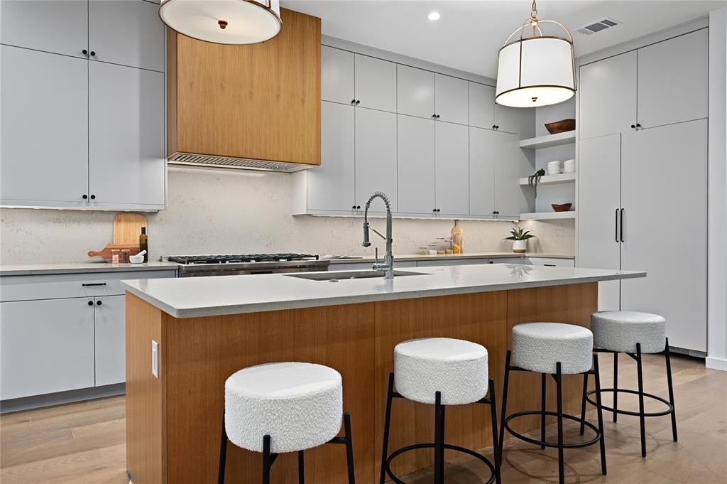 Kitchen island with stone counters, a wood range hood, and tile backsplash at 2635 Barton Hills Dr, Austin.