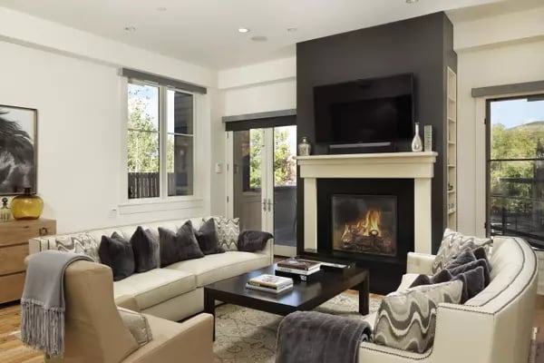 Living room with cream seating, a fireplace, and a television above the mantel.