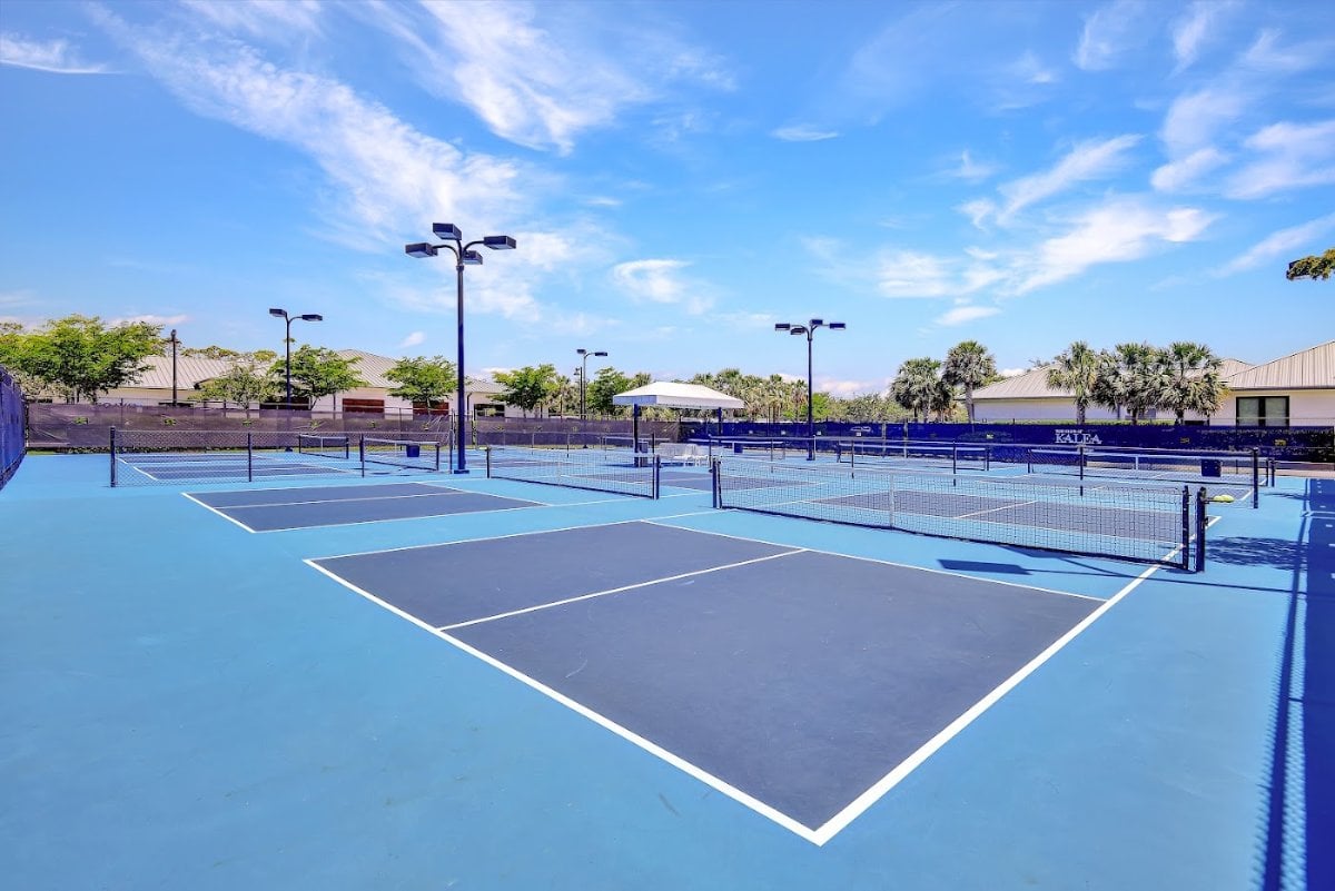 Pickleball courts at Kalea Bay, with the Kalea windscreen and the clubhouse buildings behind.