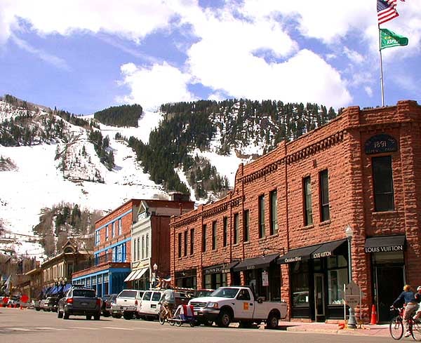 Mountain-town storefronts beneath snowy slopes, including a brick Louis Vuitton shop.