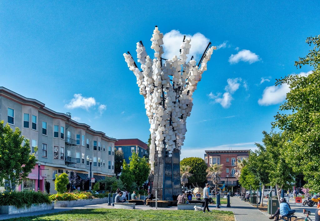 Patricia's Green in Hayes Valley surrounded by boutique shops, with public art installations and people relaxing outdoors.