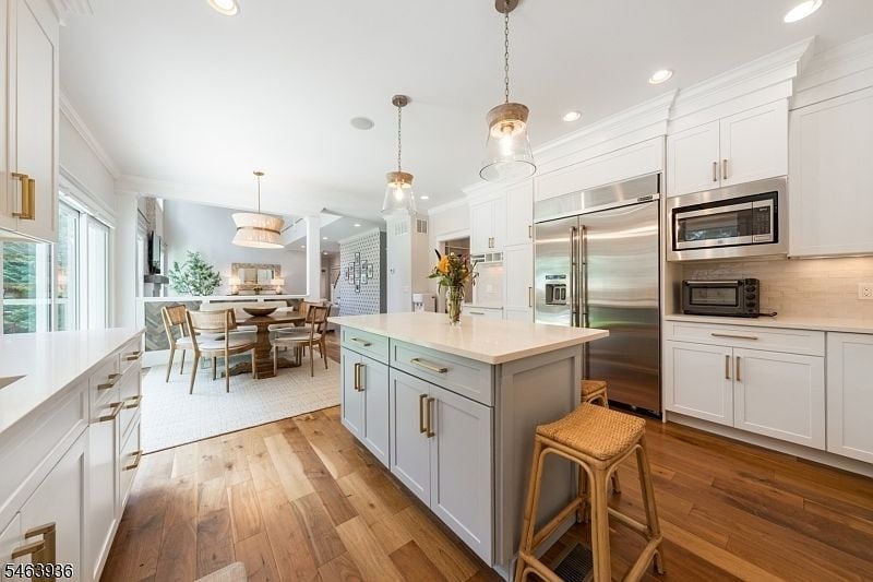 Bright kitchen with a large island, stainless steel appliances, and an adjoining dining area.