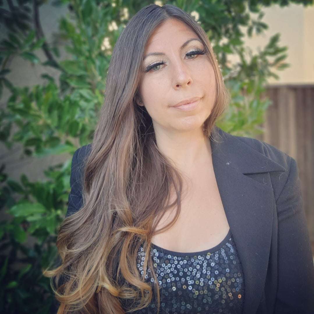 Becky Mirelez wearing a black blazer and patterned top outdoors.