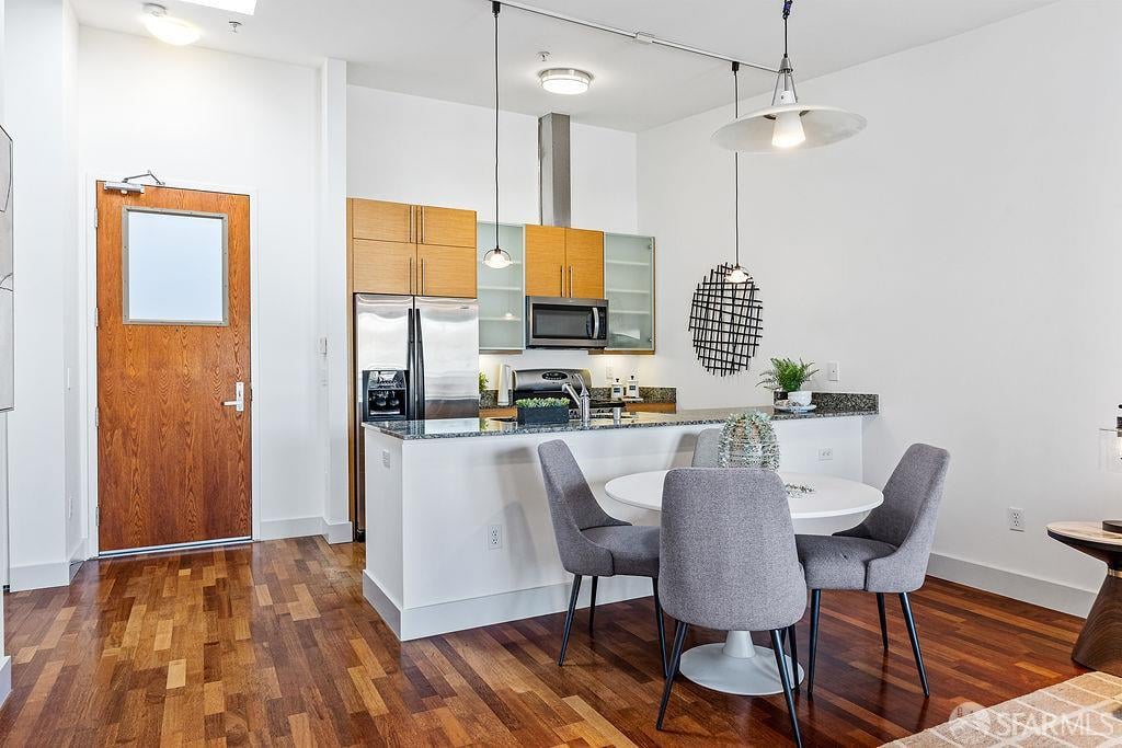 Condo kitchen and dining area with wood cabinets, stainless appliances, and a round table by the breakfast bar.