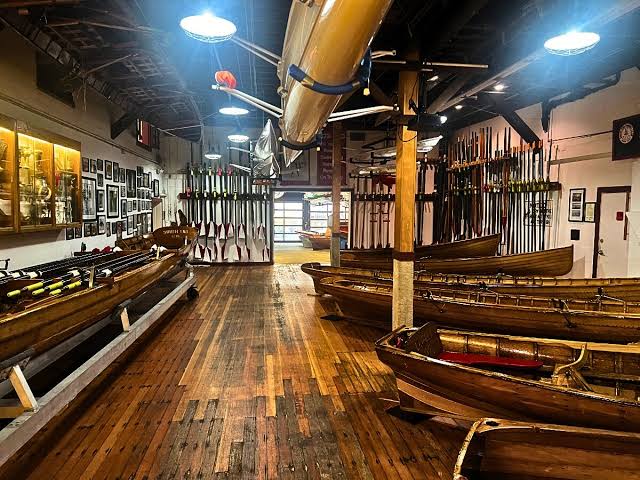 Wooden rowing boats and oars stored in vintage boathouse with polished floors