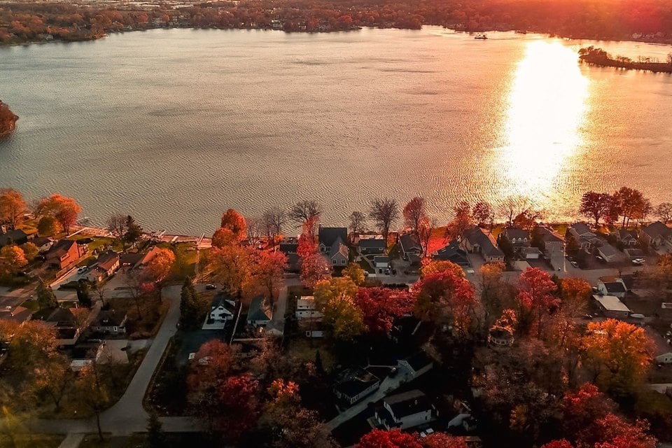 Aerial view of homes along Little Muskego Lake during sunset with fall trees