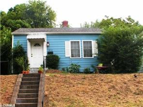 Blue single-story house with white trim, front steps, and a dry sloping lawn.