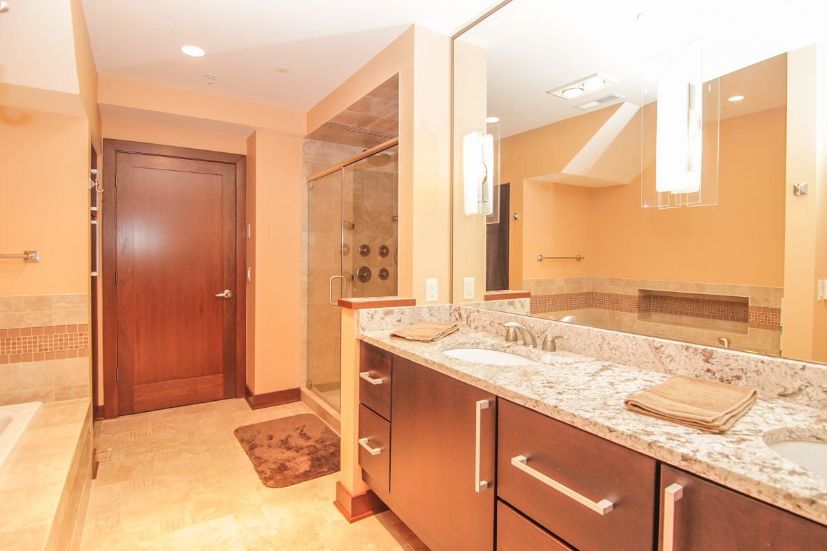 Bathroom with a long granite double vanity and a glass shower with multiple jets.