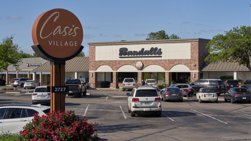 Oasis Village shopping center with Randall's grocery store and a prominent roadside sign.