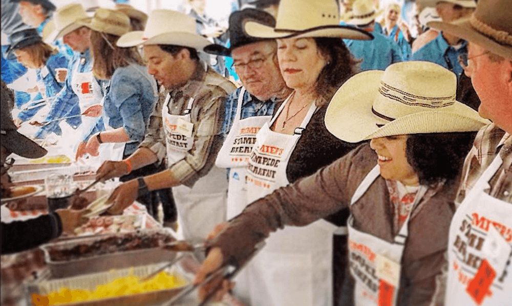 volunteers enjoying serving hot pancakes during stampede breakfast