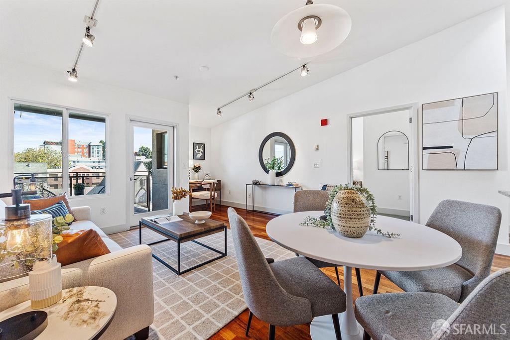 Furnished living and dining room with hardwood floors, large windows, and balcony access.
