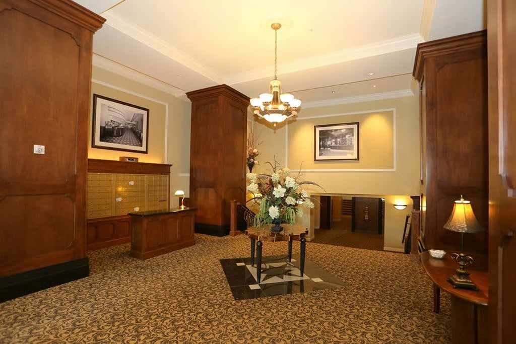 Building lobby with dark wood columns, patterned carpet, and a chandelier.