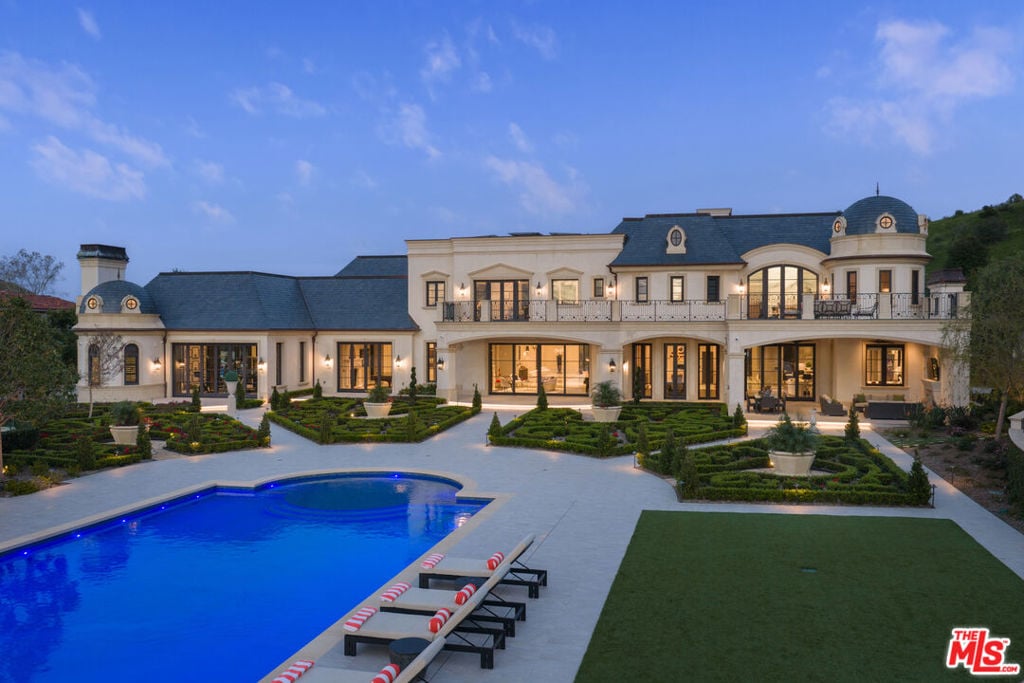 Large estate with formal gardens and a blue swimming pool at dusk.