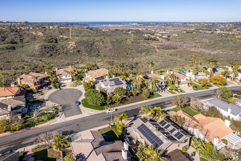 Aerial view of Carmel Valley, San Diego, showing luxury homes with solar panels, canyon preserve, and ocean in the distance—ideal for high-end real estate buyers.