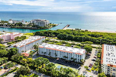 Oceanfront condominiums amid palm trees, with a beach and inlet visible along the coastline.